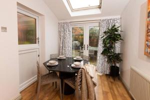 comedor con mesa, sillas y ventana en Beautiful West Didsbury 4BR Home, en Mánchester