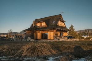 une ancienne maison en rondins assise dans un champ dans l'établissement Domek Między Dolinami, à Witów