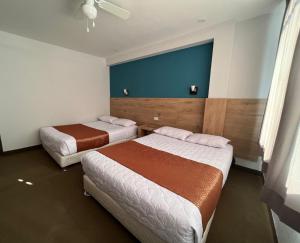 Habitación de hotel con 2 camas y pared azul en Costa Bella, en Ilo