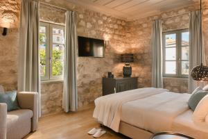 um quarto com uma cama, uma cadeira e janelas em Hydroussa Hotel Hydra em Hidra