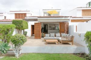 un patio con sofá y sillas en una casa en Bungalow frente al mar golf piscina, en San Miguel de Abona