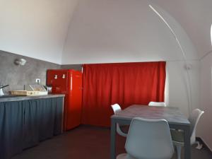 a kitchen with a table and a red refrigerator at Nido sul mare in Pantelleria