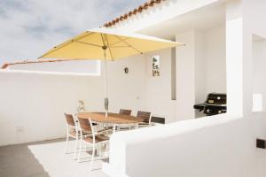 comedor con mesa y sombrilla amarilla en Bungalow frente al mar golf piscina, en San Miguel de Abona