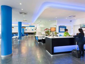 a lobby of a hospital with a woman standing at a counter at ibis budget Dresden City in Dresden