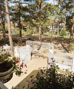 a garden with white fences and flowers and trees at vita homestay Măng Đen in Kon Von Kla