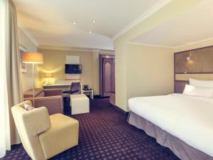 una camera d'albergo con un grande letto e una sedia di Mercure Hotel Dortmund Centrum a Dortmund