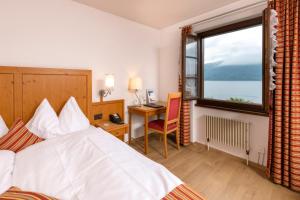 una camera da letto con un letto, una scrivania e una finestra di See & Wellnesshotel Gerbi a Weggis