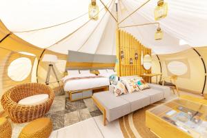 ein Schlafzimmer in einem Zelt mit einem Bett und einem Sofa in der Unterkunft fabula glamping in Kimitsu