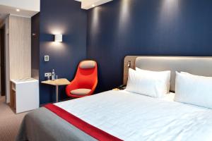 a hotel room with a bed and a red chair at Holiday Inn Express - Ringsheim, an IHG Hotel in Ringsheim