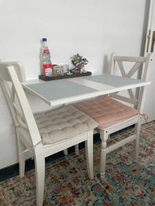 ein weißer Tisch und zwei Stühle mit einem Tisch und Getränken in der Unterkunft Einliegerwohnung in Taunusstein Bleidenstadt in Taunusstein
