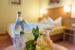 a table with a bottle and flowers on a table with a room at Vitalhotel am Stadtpark Superior in Bad Harzburg