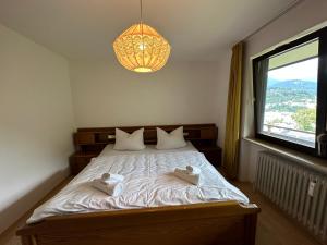 1 dormitorio con 1 cama con lámpara de araña y ventana en Frieda's Bergblick mit Hallenbad en Berchtesgaden