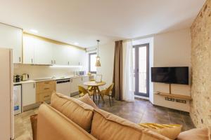 ein Wohnzimmer mit einem Sofa und eine Küche mit einem Tisch in der Unterkunft Bravissimo Mercadal, one-bedroom plus sofa bed in Girona