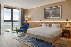 a hotel room with a bed and a blue chair at Lake Hill Mazury, a member of Radisson Individuals in Ostróda