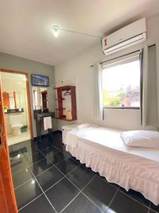 a hotel room with a bed and a window at Pousada Itaguaçu in Aparecida