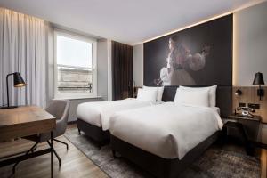 a hotel room with two beds and a large painting on the wall at Radisson RED Hotel, Liverpool in Liverpool