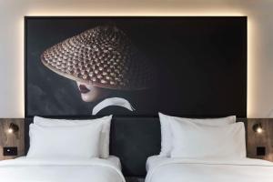 a picture of a woman with a hat above two beds at Radisson RED Hotel, Liverpool in Liverpool