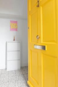 a yellow door in a room with a cabinet at Canary, 2-bed seafront flat. Pet-friendly. in Margate