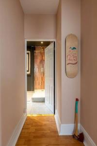 a hallway with a door and a skateboard on the wall at Canary, 2-bed seafront flat. Pet-friendly. in Margate