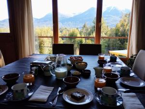 a table with food on it with a view of mountains at Huerta de los Andes - Bed and Breakfast in Villa La Angostura