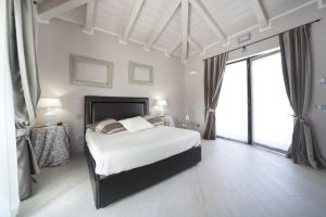 a white bedroom with a bed and large windows at Villa Castelletto in Castelletto Molina