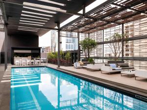 a swimming pool in a building with chairs and tables at Novotel Perth Murray Street in Perth