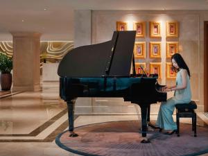 a woman sitting at a piano in a lobby at Grand Mercure Hanoi in Hanoi