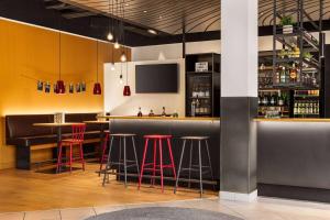a bar with red bar stools and a tv at Vienna House Easy by Wyndham Neckarsulm in Neckarsulm