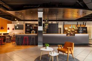 a lobby with chairs and tables and a bar at Vienna House Easy by Wyndham Neckarsulm in Neckarsulm