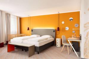 a bedroom with two beds and a desk in it at Vienna House Easy by Wyndham Neckarsulm in Neckarsulm