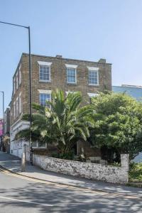 a brick building with palm trees in front of a street at Palm Heights - top floor luxury flat in Margate