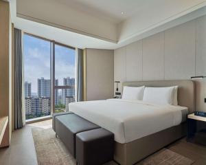 a bedroom with a large bed and a large window at Hyatt Place Yantai Development Zone in Yantai