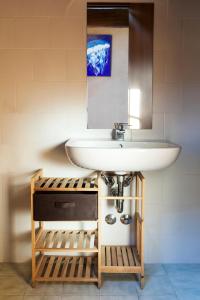 La salle de bains est pourvue d'un lavabo blanc et d'un miroir. dans l'établissement Ostello Artemista Ass. Ostelli Lombardia, à Spessa