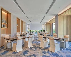 sala konferencyjna ze stołami i białymi krzesłami w obiekcie Hyatt Place Yantai Development Zone w mieście Yantai