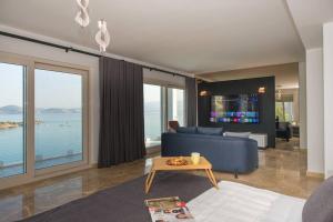 a living room with a blue couch and large windows at BEACH FRONT SUPER VİLLA Boss 2 in Bodrum City