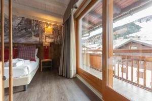 um quarto com uma cama e uma grande janela em Olimpia Hotel em Bormio