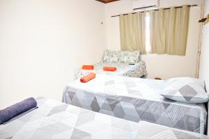 Habitación con 2 camas y una silla. en Hostel mineiros, en Aracaju