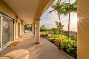 een veranda met uitzicht op de oceaan en palmbomen bij Villa de lujo con piscina y vistas al mar in Tacoronte