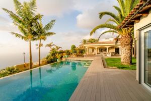 een zwembad voor een huis met palmbomen bij Villa de lujo con piscina y vistas al mar in Tacoronte