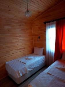 two beds in a wooden room with a window at Chirali Eco Villa in Kemer