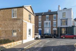 a brick building with cars parked in a parking lot at SEA BREEZE APARTMENT in Margate