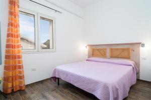 a bedroom with a bed and two windows at Holiday vista mare in Cala Gonone