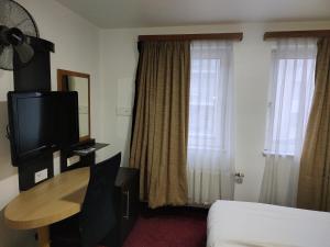 une chambre d'hôtel avec un lit, une table et une télévision dans l'établissement Hotel Evergreen, à Bruxelles
