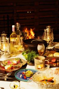 君津市にあるfabula glampingのテーブルの上に盛り付けられた料理とワインを楽しめます。