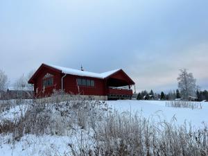 una casa roja con nieve encima en Åsengården Boende & Gästgiveri, en Asen