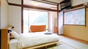 a bedroom with a bed and a large window at Miharashinoyado Fronden in Hita
