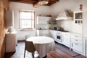 a kitchen with a white table and a white refrigerator at Ostello Artemista Ass. Ostelli Lombardia in Spessa