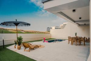 a patio with a table and chairs and an umbrella at Voyage Private Pool & Beach At Your Doorstep in Abu Dhabi