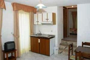 a kitchen with a sink and a tv in a room at Odyssey Hotel Apartments in Karpathos +21 photos