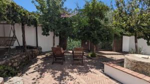 two chairs and a table in a courtyard with trees at Molino Viejo de Salar in Salar +25 photos